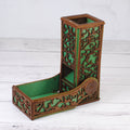 Decorative wooden pen holder with intricate carvings on a white wooden surface
