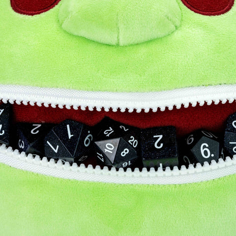 Green plush toy with a zipper mouth displaying dice