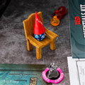 Gnome figurine with a red hat and dice on a wooden chair, surrounded by gaming accessories.