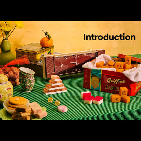 Vintage-style display with snacks, a clock, and a box labeled 'Griffin's' on a green tablecloth.