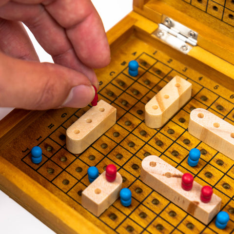 Hand playing a traditional game with wooden pieces on a yellow board