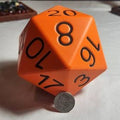 Orange polyhedral dice with black numbers on a white surface