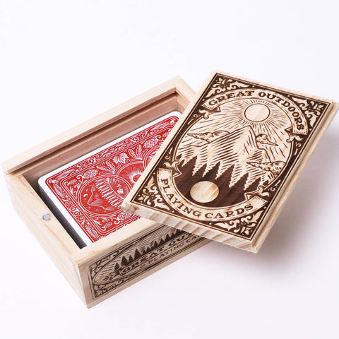 Open box of playing cards with a red card peeking out on a white background