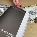 Open book with a hand holding dice on a tiled floor