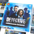 Detective: A Modern Crime Board Game Season One box set displayed on a white surface, surrounded by game components including character cards and rulebook pages.
