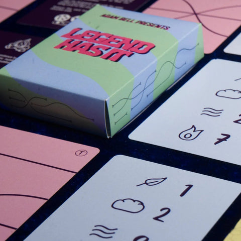 Card game packaging with cards featuring symbols and text on a dark surface