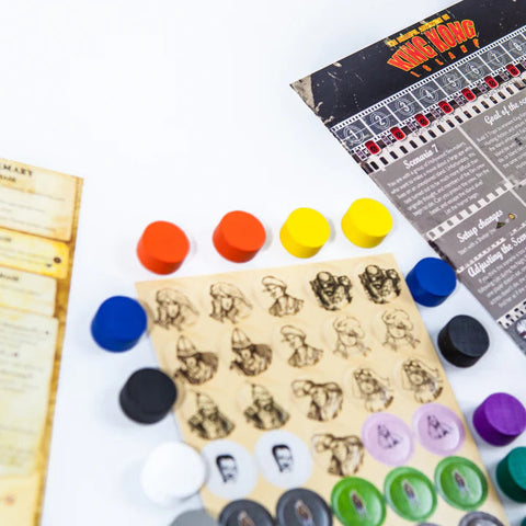 Board game components including cards, tokens, and a board with game pieces on a white surface.