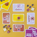 Board game components including cards and dice on a yellow background