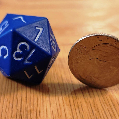 Blue polyhedral dice next to a coin on a wooden surface