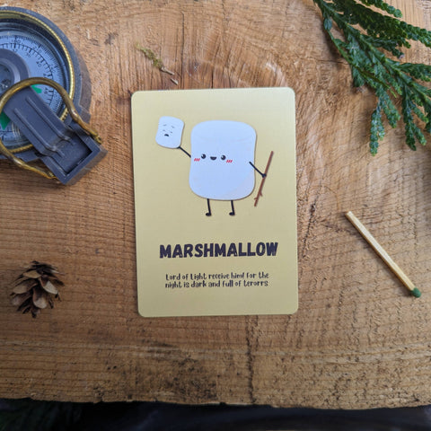 Marshmallow character card on a wooden surface with a compass and matchbook.