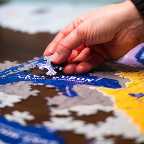 Hand placing a puzzle piece on a map of Lauren, Michigan.