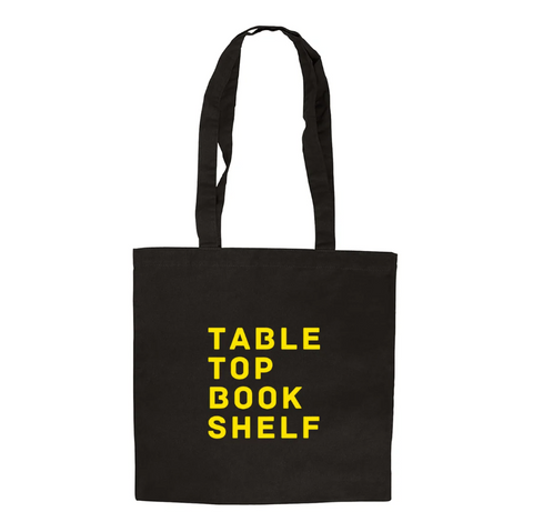 Black tote bag with yellow text 'TABLE TOP BOOK SHELF' on a white background